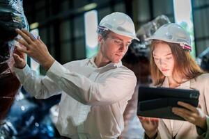 Sales manager and factory owner in suits negotiating selling robots used in the factory. Business engineers meeting and checking new machine robot. Workers walking at warehouse welding machine. photo