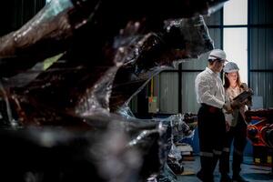 ventas gerente y fábrica propietario en trajes negociando de venta robots usado en el fábrica. negocio ingenieros reunión y comprobación nuevo máquina robot. trabajadores caminando a almacén soldadura máquina. foto