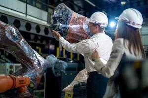 negocio ingenieros reunión y comprobación nuevo máquina robot. trabajadores caminando a almacén industria soldadura máquina. negocio negociación conceptos y tecnología. mujer utilizando inteligente tableta a presente hombre. foto