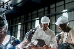 Factory engineers inspecting on machine with smart tablet. Worker works at machine robot arm. The welding machine with a remote system in an industrial factory. Artificial intelligence concept. photo
