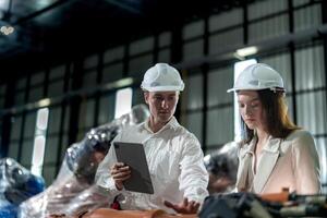 Factory engineers inspecting on machine with smart tablet. Worker works at machine robot arm. The welding machine with a remote system in an industrial factory. Artificial intelligence concept. photo