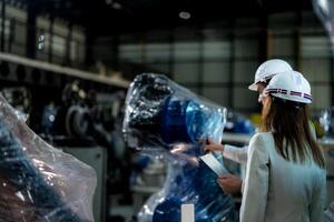 negocio ingenieros reunirse y cheque controlar pesado máquina robot brazo. diverso equipo de industrial robótica ingenieros reunido alrededor máquina. profesional maquinaria operador utilizar industrial digital tableta. foto