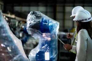Business engineers meet and check control heavy machine robot arm. Diverse Team of Industrial Robotics Engineers Gathered Around machine. Professional Machinery Operator Use Industrial Digital Tablet. photo