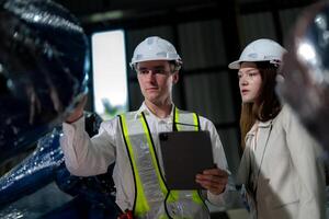 Sales manager and factory owner in suits negotiating selling robots used in the factory. Business engineers meeting and checking new machine robot. Workers walking at warehouse welding machine. photo