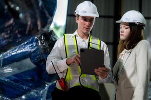 Factory engineers inspecting on machine with smart tablet. Worker works at machine robot arm. The welding machine with a remote system in an industrial factory. Artificial intelligence concept. photo