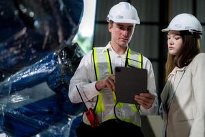 Factory engineers inspecting on machine with smart tablet. Worker works at machine robot arm. The welding machine with a remote system in an industrial factory. Artificial intelligence concept. photo
