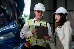 Sales manager and factory owner in suits negotiating selling robots used in the factory. Business engineers meeting and checking new machine robot. Workers walking at warehouse welding machine. photo