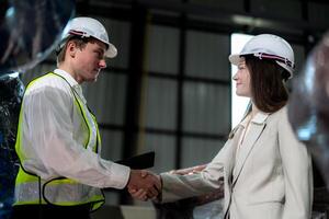 Sales manager and factory owner in suits negotiating selling robots used in the factory. Business engineers meeting and checking new machine robot. Workers walking at warehouse welding machine. photo