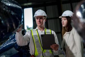 Sales manager and factory owner in suits negotiating selling robots used in the factory. Business engineers meeting and checking new machine robot. Workers walking at warehouse welding machine. photo