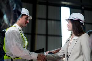 Sales manager and factory owner in suits negotiating selling robots used in the factory. Business engineers meeting and checking new machine robot. Workers walking at warehouse welding machine. photo