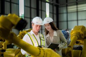 Sales manager and factory owner in suits negotiating selling robots used in the factory. Business engineers meeting and checking new machine robot. Workers walking at warehouse welding machine. photo