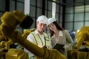 ventas gerente y fábrica propietario en trajes negociando de venta robots usado en el fábrica. negocio ingenieros reunión y comprobación nuevo máquina robot. trabajadores caminando a almacén soldadura máquina. foto