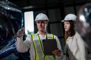 Sales manager and factory owner in suits negotiating selling robots used in the factory. Business engineers meeting and checking new machine robot. Workers walking at warehouse welding machine. photo