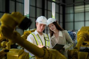 Sales manager and factory owner in suits negotiating selling robots used in the factory. Business engineers meeting and checking new machine robot. Workers walking at warehouse welding machine. photo