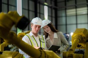 Sales manager and factory owner in suits negotiating selling robots used in the factory. Business engineers meeting and checking new machine robot. Workers walking at warehouse welding machine. photo