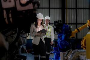 negocio mujer y hombre reunión y comprobación nuevo máquina robot. ingeniero caminando a almacén industria máquina. negocio negociación conceptos y tecnología. mujer es utilizando inteligente tableta a presente hombre. foto