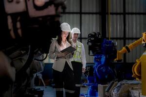 negocio mujer y hombre reunión y comprobación nuevo máquina robot. ingeniero caminando a almacén industria máquina. negocio negociación conceptos y tecnología. mujer es utilizando inteligente tableta a presente hombre. foto