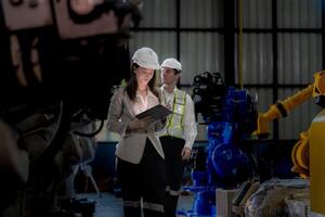 negocio mujer y hombre reunión y comprobación nuevo máquina robot. ingeniero caminando a almacén industria máquina. negocio negociación conceptos y tecnología. mujer es utilizando inteligente tableta a presente hombre. foto