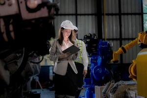 negocio mujer y hombre reunión y comprobación nuevo máquina robot. ingeniero caminando a almacén industria máquina. negocio negociación conceptos y tecnología. mujer es utilizando inteligente tableta a presente hombre. foto