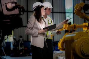 negocio mujer y hombre reunión y comprobación nuevo máquina robot. ingeniero caminando a almacén industria máquina. negocio negociación conceptos y tecnología. mujer es utilizando inteligente tableta a presente hombre. foto