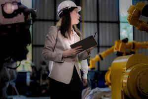 Business woman and man meeting and checking new machine robot. Engineer walking at warehouse industry machine. business negotiation concepts and technology. woman is Using smart Tablet to present man. photo