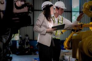 negocio mujer y hombre reunión y comprobación nuevo máquina robot. ingeniero caminando a almacén industria máquina. negocio negociación conceptos y tecnología. mujer es utilizando inteligente tableta a presente hombre. foto