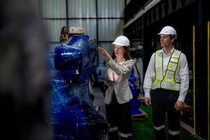 Business woman and man meeting and checking new machine robot. Engineer walking at warehouse industry machine. business negotiation concepts and technology. woman is Using smart Tablet to present man. photo