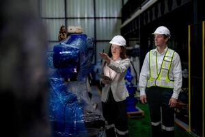 Business woman and man meeting and checking new machine robot. Engineer walking at warehouse industry machine. business negotiation concepts and technology. woman is Using smart Tablet to present man. photo