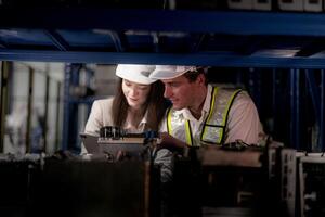 checking and inspecting metal machine part items for shipping. male and woman worker checking the store factory. industry factory warehouse. The warehouse of spare part for machinery and vehicles. photo