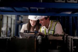 checking and inspecting metal machine part items for shipping. male and woman worker checking the store factory. industry factory warehouse. The warehouse of spare part for machinery and vehicles. photo