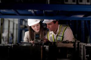 técnico ingenieros equipo comprobación el máquina y mantenimiento servicio. trabajadores mirando a de repuesto partes en valores a almacén fábrica. obrero con un Lista de Verificación mirando en parte de máquina partes. foto