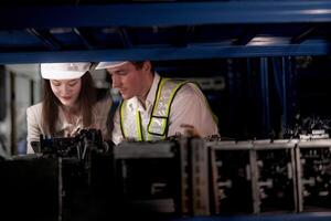 comprobación y inspeccionando metal máquina parte artículos para envío. masculino y mujer trabajador comprobación el Tienda fábrica. industria fábrica depósito. el almacén de de repuesto parte para maquinaria y vehículos foto