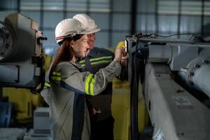 ingenieros cheque controlar pesado máquina robot brazo. diverso equipo de industrial robótica ingenieros reunido alrededor máquina. profesional maquinaria operadores reparar eléctrico robot en brillante digital panel. foto