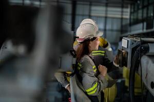 ingenieros cheque controlar pesado máquina robot brazo. diverso equipo de industrial robótica ingenieros reunido alrededor máquina. profesional maquinaria operadores reparar eléctrico robot en brillante digital panel. foto