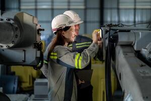 engineers check control heavy machine robot arm. Diverse Team of Industrial Robotics Engineers Gathered Around Machine. Professional Machinery Operators repair electric robot on bright digital panel. photo