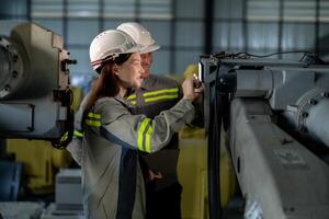 ingenieros cheque controlar pesado máquina robot brazo. diverso equipo de industrial robótica ingenieros reunido alrededor máquina. profesional maquinaria operadores reparar eléctrico robot en brillante digital panel. foto