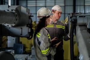 ingenieros cheque controlar pesado máquina robot brazo. diverso equipo de industrial robótica ingenieros reunido alrededor máquina. profesional maquinaria operadores reparar eléctrico robot en brillante digital panel. foto