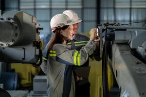 engineers check control heavy machine robot arm. Diverse Team of Industrial Robotics Engineers Gathered Around Machine. Professional Machinery Operators repair electric robot on bright digital panel. photo
