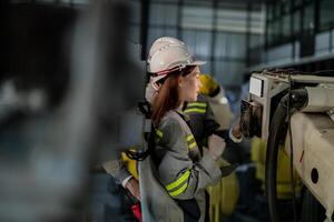 engineers check control heavy machine robot arm. Diverse Team of Industrial Robotics Engineers Gathered Around Machine. Professional Machinery Operators repair electric robot on bright digital panel. photo