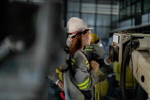 engineers check control heavy machine robot arm. Diverse Team of Industrial Robotics Engineers Gathered Around Machine. Professional Machinery Operators repair electric robot on bright digital panel. photo