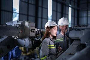 engineers check control heavy machine robot arm. Diverse Team of Industrial Robotics Engineers Gathered Around Machine. Professional Machinery Operators repair electric robot on bright digital panel. photo