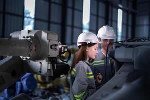 engineers check control heavy machine robot arm. Diverse Team of Industrial Robotics Engineers Gathered Around Machine. Professional Machinery Operators repair electric robot on bright digital panel. photo