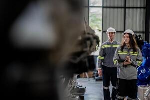 engineers check control heavy machine robot arm. Diverse Team of Industrial Robotics Engineers Gathered Around Machine. Professional Machinery Operators repair electric robot on bright digital panel. photo