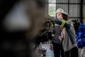 Factory engineer woman inspecting on machine with smart tablet. Worker works at machine robot arm. The welding machine with a remote system in an industrial factory. Artificial intelligence concept. photo