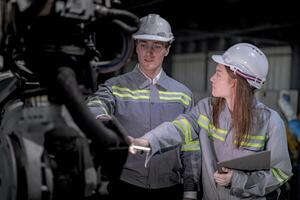 negocio ingenieros reunirse y cheque controlar pesado máquina robot brazo. diverso equipo de industrial robótica ingenieros reunido alrededor máquina. profesional maquinaria operador utilizar industrial digital tableta. foto