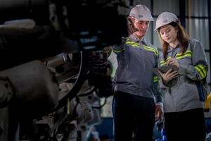 Factory engineer woman inspecting on machine with smart tablet. Worker works at machine robot arm. The welding machine with a remote system in an industrial factory. Artificial intelligence concept. photo