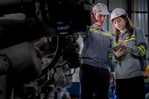 Factory engineer woman inspecting on machine with smart tablet. Worker works at machine robot arm. The welding machine with a remote system in an industrial factory. Artificial intelligence concept. photo