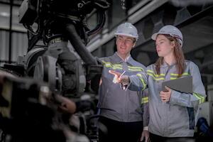 Sales manager and factory owner in suits negotiating selling robots used in the factory. Business engineers meeting and checking new machine robot. Workers walking at warehouse welding machine. photo