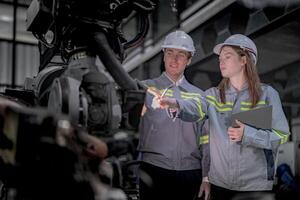 Sales manager and factory owner in suits negotiating selling robots used in the factory. Business engineers meeting and checking new machine robot. Workers walking at warehouse welding machine. photo
