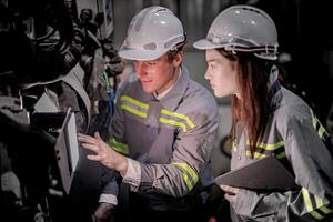 Sales manager and factory owner in suits negotiating selling robots used in the factory. Business engineers meeting and checking new machine robot. Workers walking at warehouse welding machine. photo